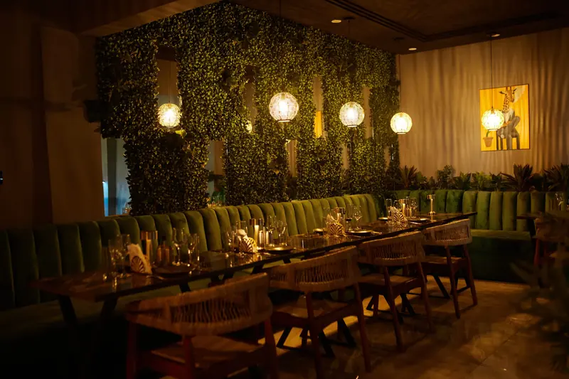 The Hayvin Restaurant: a dining room with a green plant wall, warm pendant lights and set tables